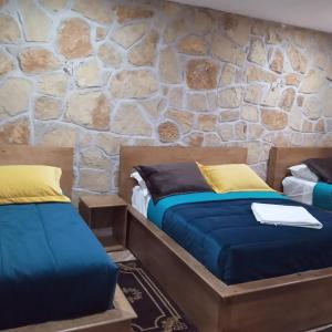 - 2 lits dans une chambre avec un mur en pierre dans l'établissement Le Gite du Barrage, à Zaouia Ben Smine
