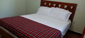 a bed with a checkered blanket and white pillows at Sumawe Suites in Karatu