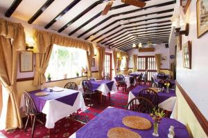 ランゴレンにあるAbbey Grange Hotelの紫色のテーブルと椅子が備わるダイニングルーム