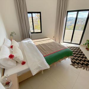 a bedroom with a bed with white pillows and a window at Nu Fifty Two in Amman