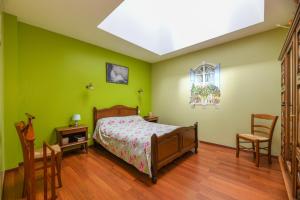 1 dormitorio con paredes verdes, 1 cama y 2 sillas en gîtes de l'Hôpiteau, en LʼOie