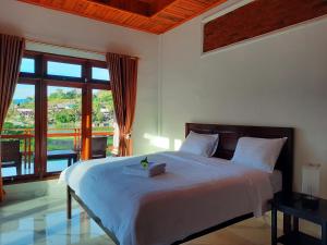 a bedroom with a bed and a large window at Juma cottages in Tuk Tuk