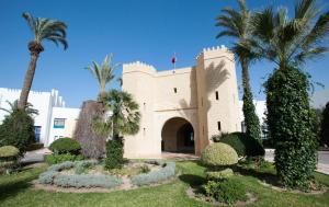 un bâtiment avec des palmiers en face de celui-ci dans l'établissement Mahdia Palace Thalasso, à Mahdia