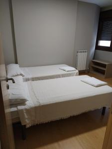 a bedroom with two beds with white sheets and a window at APARTAMENTO SENDA SUR in Porriño