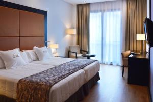 um quarto de hotel com uma cama grande e uma cadeira em Gran Hotel Don Manuel em Cáceres