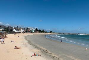 un groupe de personnes sur une plage près de l'océan dans l'établissement Lomener - La Goelette - studios à 450m de la plage, à Ploemeur