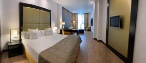 a hotel room with a large bed and a television at Gran Hotel Don Manuel in Cáceres