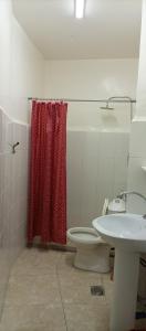 a bathroom with a toilet and a red shower curtain at Al Midan Hotel in Amman