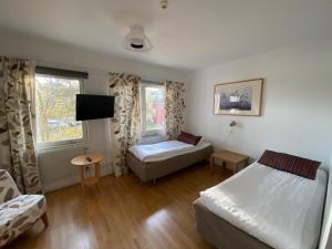 a bedroom with two beds and a tv in it at Nynäsgården Hotell & Konferens in Nynäshamn