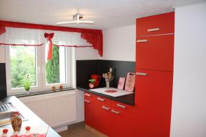 a kitchen with red cabinets and a window at Ferienwohnung-Schrammsteinblick in Lichtenhain