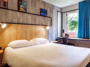 a bedroom with a large white bed and a window at ibis Tours Sud in Chambray-lès-Tours