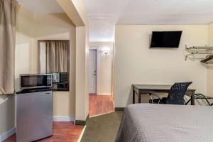 um quarto com uma cama e uma secretária com um micro-ondas em Rodeway Inn Lake George Outlets em Lake George