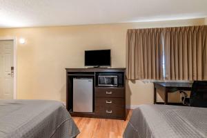 a hotel room with two beds and a flat screen tv at Rodeway Inn Lake George Outlets in Lake George