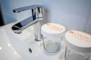 a bathroom sink with a faucet and two cups at Comfort Hotel Frankfurt Central Station in Frankfurt/Main