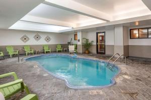 una piscina en una habitación de hotel con sillas y mesas en Comfort Inn Madison en Madison