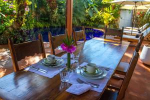 a wooden table with plates and a flower on it at Casa Simone Pousada in Paraty