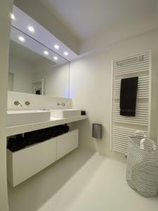 bagno bianco con lavandino e specchio di OSKAR luxe appartement op zeedijk met zeezicht a Ostenda