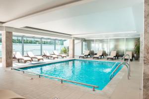 a pool in a hotel lobby with chairs and tables at Garden City Hotel Konjic in Konjic