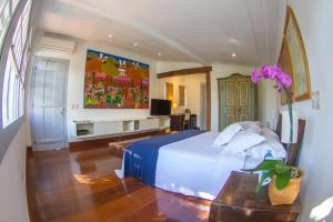Casa Simone Pousada في باراتي: غرفة نوم فيها سرير وتلفزيون