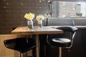 a table with two chairs and vases of flowers on it at Forth Apartments in Kirkcaldy