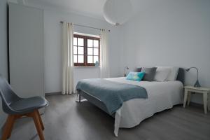 a white bedroom with a bed and a chair at A Casa na Foz ! West is the Best ! in Foz do Arelho