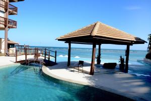 a swimming pool with a gazebo next to the ocean at BARRA BALI 04 quartos Barra de São Miguel in Barra de São Miguel