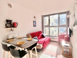 een woonkamer met een tafel en een rode bank bij ISOLA Front de Neige - STUDIO in Isola 2000