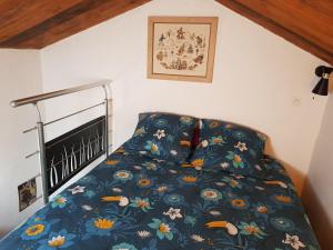 a bed with a blue bedspread with flowers on it at Petit chalet savoyard in Domancy