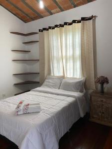 ein Schlafzimmer mit einem weißen Bett und einem Fenster in der Unterkunft Loft Largo do Ó in Tiradentes