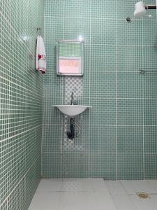 ein grün gefliestes Bad mit einem Waschbecken und einem Spiegel in der Unterkunft Loft Largo do Ó in Tiradentes