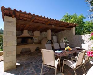 un patio con tavolo, sedie e forno all'aperto di Villa Maragoudi ad Arménoi