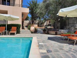 Arménoi的住宿－Villa Maragoudi，房屋旁的游泳池配有椅子和遮阳伞