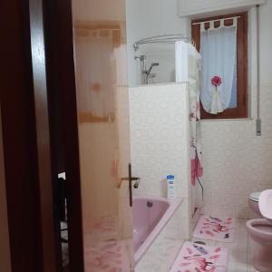 La salle de bains est pourvue d'une baignoire rose et de toilettes. dans l'établissement B&B Da Andreina, à Guspini