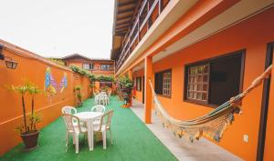 um pátio com mesas e cadeiras brancas num edifício laranja em Pousada Village Garopaba em Garopaba