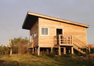 a small wooden house on a hill with a porch at Charrua de Punta colorada in Punta Colorada