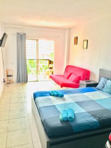 a bedroom with two beds and a red couch at San Jose guesthouse Edificio S de Sol in Puerto de la Cruz