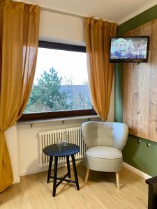 Zimmer mit einem Stuhl, einem Tisch und einem Fenster in der Unterkunft Landgasthaus Löwen mit Gästehaus in Holzhausen