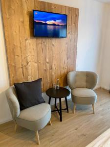 霍茲哈森的住宿－藍哥羅迷賓館，客厅配有两把椅子和墙上的电视