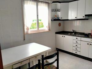a kitchen with white cabinets and a white counter top at Vivienda uso turistico Los Nogales in Foz