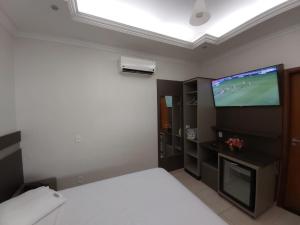 a bedroom with a bed and a flat screen tv at Pousada DuKalango in Caldas Novas