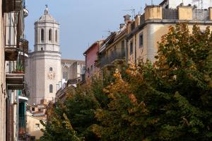 a building with a clock tower and a tree at Onyar apartments Rambla de la llibertat 27 in Girona