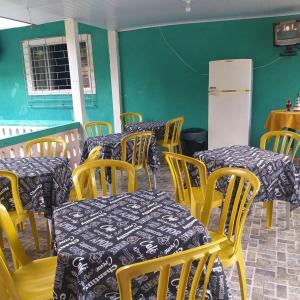 um restaurante com mesas e cadeiras amarelas e um frigorífico branco em Pousada Recanto Do sagui em Morretes