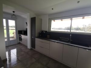 a kitchen with white cabinets and a large window at Le pigeonnier de La Mouline in Viterbe +2 photos