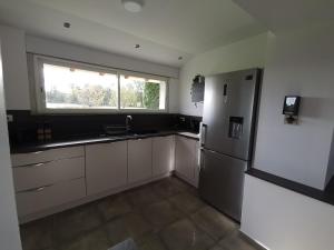 a kitchen with a refrigerator and a window at Le pigeonnier de La Mouline in Viterbe