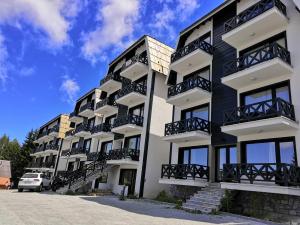 科帕奥尼克Silver Kop apartmani的公寓大楼设有阳台和停车场