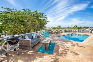 a patio with a couch and a grill next to a swimming pool at Villa Caiquetio in Jan Thiel