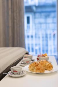a table with a plate of croissants and cups of coffee at Dante Square in Naples
