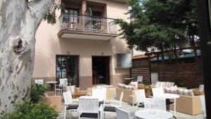 een patio met witte stoelen en tafels voor een gebouw bij Enalion Hotel in Kala Nera