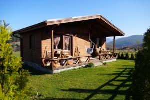 eine Holzhütte mit Tischen und Stühlen auf einem Feld in der Unterkunft Hotel Orbel in Dobrinischte