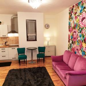 Paradise Apartman في ميشكولتْس: غرفة معيشة مع أريكة أرجوانية وكراسي خضراء